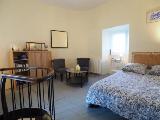 Une chambre avec un petit salon et un escalier en colimaçon.