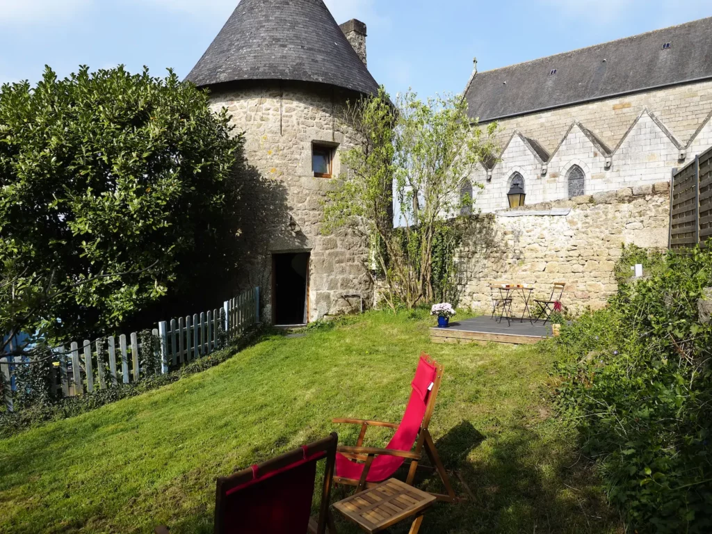 Un salon de jardin sur la pelouse, la tour médiévale est à l'angle du jardin.
